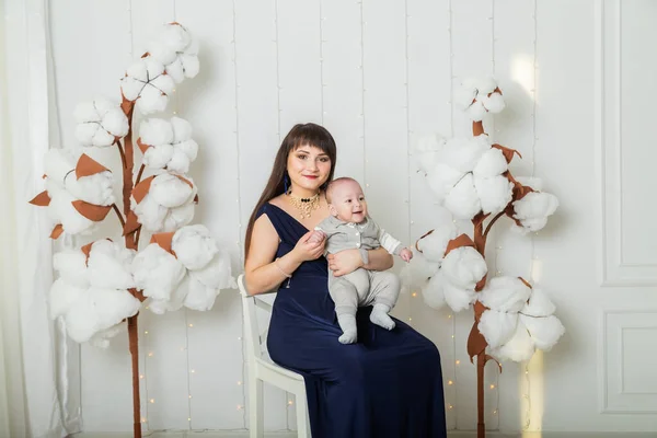 Bonne mère en robe de soirée avec un enfant dans un studio photo . — Photo