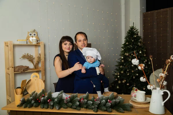 Bela família feliz e jovem com uma criança na cozinha no Ano Novo . — Fotografia de Stock