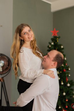 Mutlu karı koca evdeki Noel ağacında. Koca, karısını kollarına alır..