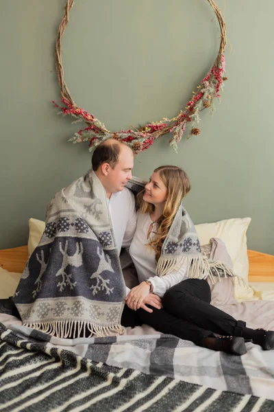 Gelukkige minnaars op het bed in de nieuwjaarskamer. Vrolijk kerstfeest 2020. — Stockfoto