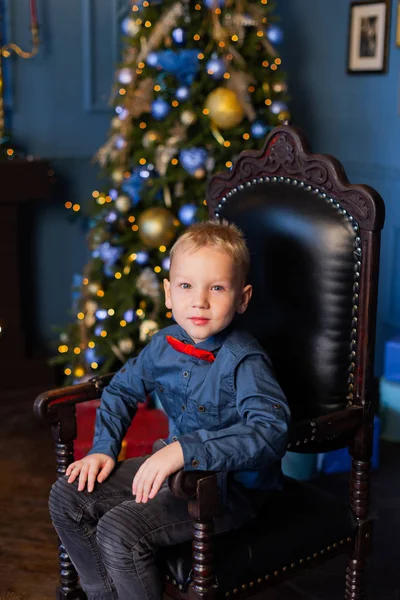 Красивий хлопчик сидить на кріслі в новорічному декорі . — стокове фото
