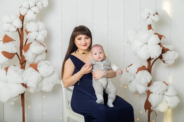 Szczęśliwa matka w sukni wieczorowej z dzieckiem w studiu fotograficznym. — Zdjęcie stockowe