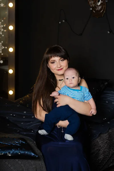 Mãe feliz em vestido de noite com uma criança em um estúdio de fotos . — Fotografia de Stock