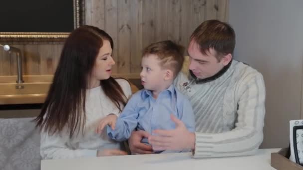 Famille heureuse avec un enfant dans la cuisine dans un intérieur moderne . — Video