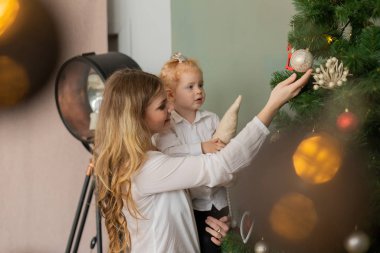 Güzel, mutlu bir anne ve Noel ağacında kollarında bir kız çocuğu. Mutlu Noeller 2020.