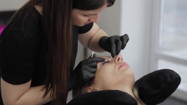 Profesionální kosmetička v salonu krásy maluje řasy na klienta. — Stock video