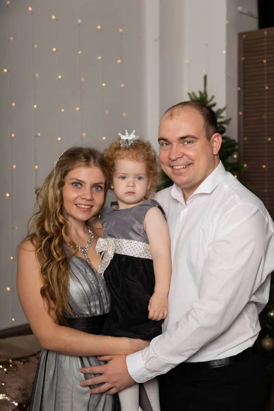 Linda jovem família feliz com uma criança em seus braços na véspera de Ano Novo. Ano Novo 2020 . — Fotografia de Stock