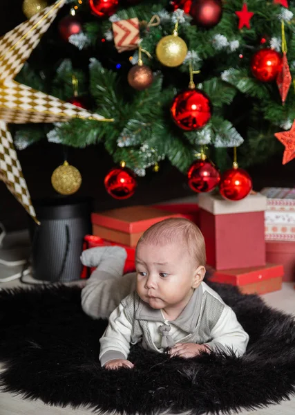 Menino bonito no chão pela árvore de Ano Novo . — Fotografia de Stock