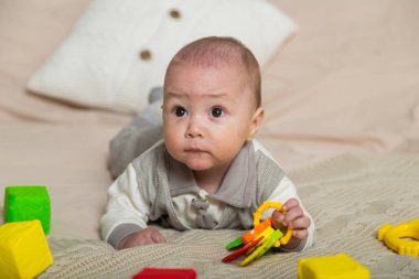 Parlak bir yatakta, çocuk oyuncaklarıyla sevimli küçük bir çocuk..