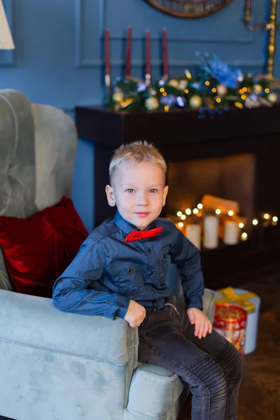 Красивий хлопчик сидить на кріслі в новорічному декорі . — стокове фото
