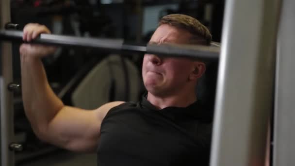 Professional athlete trains the shoulders with a barbell. — Stock Video