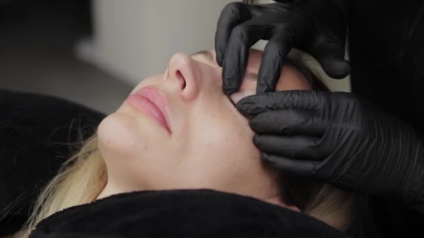 Esthéticienne professionnelle dans un salon de beauté colle une doublure en silicone pour la plastification des cils . — Video