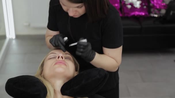 A professional beautician in a beauty salon performs eyelash lamination procedure. — Stock Video