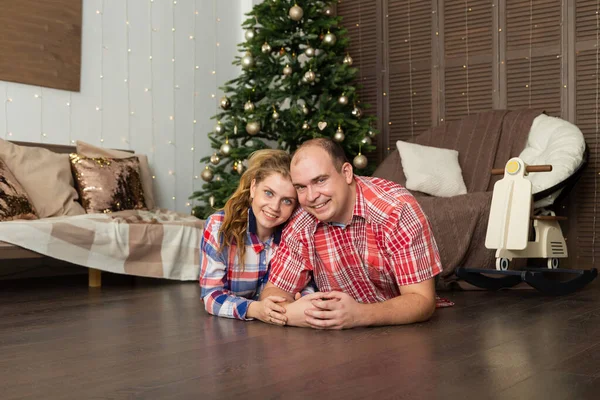 Jeune couple heureux amoureux sur le sol par l'arbre du Nouvel An . — Photo
