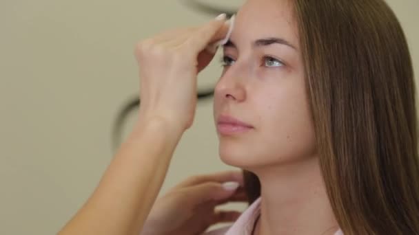 Επαγγελματική make-up καλλιτέχνης σκουπίζει το πρόσωπο του πελάτη με βαμβάκι τολύπια. — Αρχείο Βίντεο
