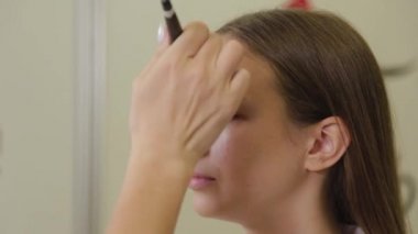 Profesyonel makyöz, müşterilerinin yüzüne temel kremi sürerken fırça kullanır.