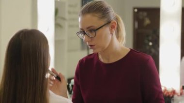 Profesyonel makyöz, müşterilerinin yüzüne temel kremi sürerken fırça kullanır.