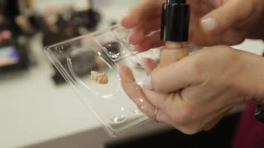 Profesyonel makyöz kadın palette makyaj kremi karıştırıyor..