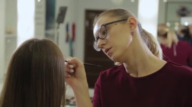 Profesyonel makyöz bir güzellik salonunun müşterisine kaş boyar..