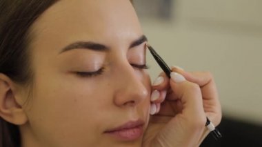 Profesyonel göz makyajı. Makyaj sanatçısı, kuaförde özel fırçası olan genç bir kadına makyaj yapıyor..