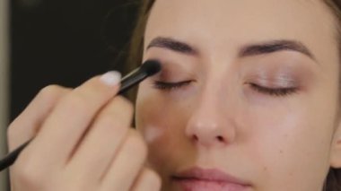 Profesyonel göz makyajı. Makyaj sanatçısı, kuaförde özel fırçası olan genç bir kadına makyaj yapıyor..