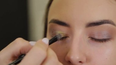 Profesyonel göz makyajı. Makyaj sanatçısı, kuaförde özel fırçası olan genç bir kadına makyaj yapıyor..