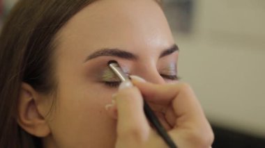 Profesyonel göz makyajı. Makyaj sanatçısı, kuaförde özel fırçası olan genç bir kadına makyaj yapıyor..