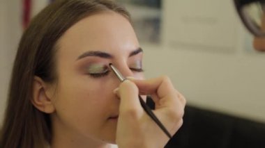 Profesyonel göz makyajı. Makyaj sanatçısı, kuaförde özel fırçası olan genç bir kadına makyaj yapıyor..
