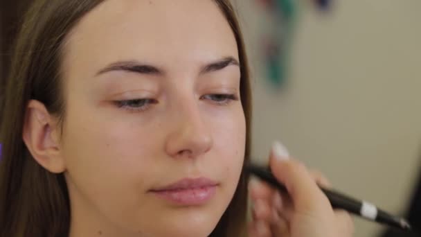 Artista de maquiagem profissional aplica creme de fundação no rosto dos clientes com escova . — Vídeo de Stock