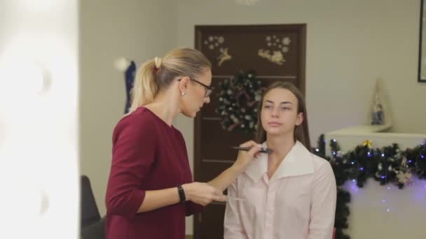 Professionele make-up kunstenaar brengt foundation cream op klanten gezicht met borstel. — Stockvideo
