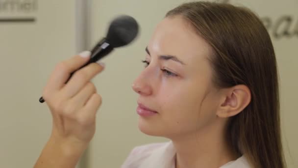 Artista de maquillaje profesional está aplicando polvo a la cara de los clientes con un cepillo . — Vídeos de Stock