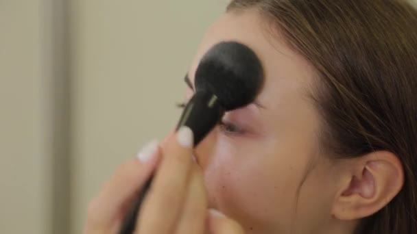 Professionell makeupartist applicerar puder på klientens ansikte med en borste. — Stockvideo