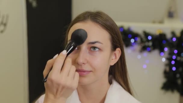 Professionell makeupartist applicerar puder på klientens ansikte med en borste. — Stockvideo