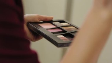 Elinde palet olan profesyonel bir makyöz. Makyaj yapıyor..