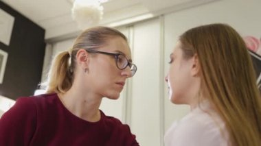 Profesyonel makyöz, güzellik salonunun müşterisine göz farı sürüyor..