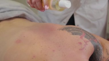 Profesyonel kadın masör bir erkeğin sırtında masaj yapıyor. Güzellik salonunda masaj..