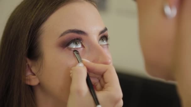 Artista de maquiagem profissional coloca sombra nos olhos de um cliente de um salão de beleza . — Vídeo de Stock