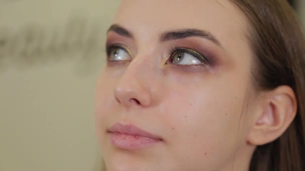 Artista de maquillaje profesional pone sombra de ojos en un cliente de un salón de belleza . — Vídeo de stock