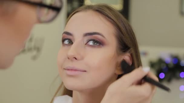 Maquilleur professionnel met ombre à paupières sur un client d'un salon de beauté . — Video