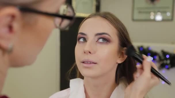 Artista de maquiagem profissional coloca sombra nos olhos de um cliente de um salão de beleza . — Vídeo de Stock