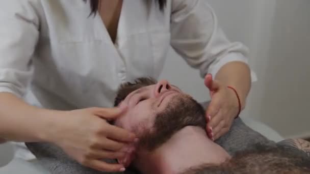 Professional woman masseur makes lymphatic massage to a man. Facial and cervical massage. — Stock Video