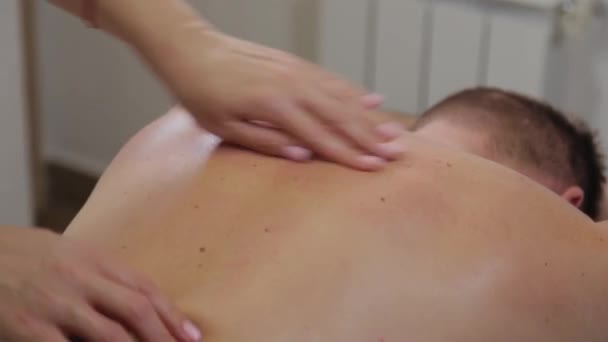 Mulher massagista profissional fazendo massagem nas costas de um homem. Massagem no salão de beleza . — Vídeo de Stock