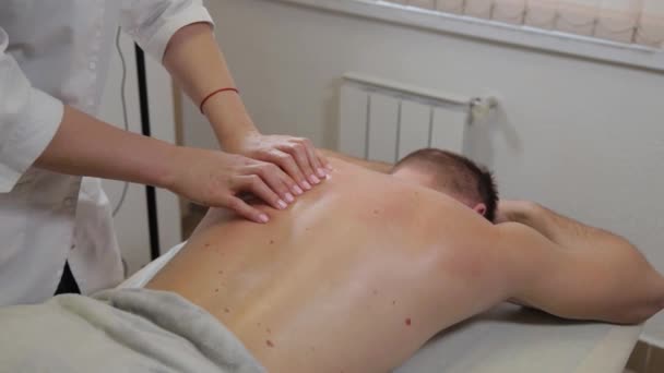 Professionelle Masseurin bei einer Massage auf dem Rücken eines Mannes. Massage im Schönheitssalon. — Stockvideo