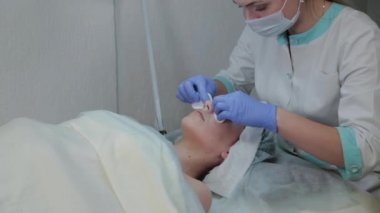 Profesyonel kozmetikçi kadın ıslak mendille müşterilerin yüzündeki maskeyi çıkarıyor..