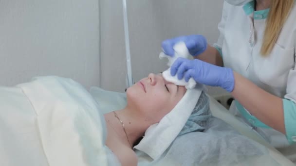 Mujer esteticista profesional se frota la cara antes del procedimiento con toallitas húmedas . — Vídeo de stock