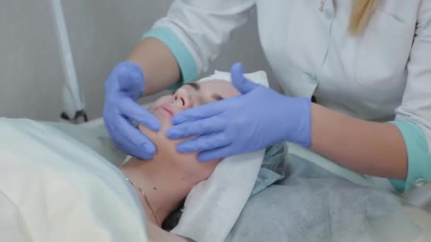 Mulher esteticista profissional esfrega o rosto antes do procedimento com toalhetes molhados . — Vídeo de Stock