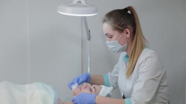 Mujer esteticista profesional se frota la cara antes del procedimiento con toallitas húmedas . — Vídeos de Stock