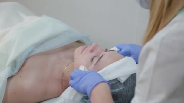 Професійна косметолог потирає обличчя перед процедурою мокрими серветками . — стокове відео