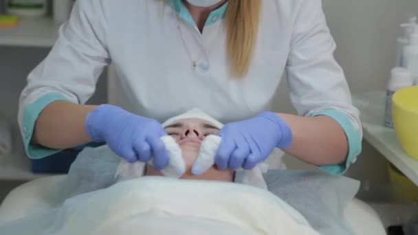 Profesyonel güzellik uzmanı kadın ameliyattan önce yüzünü ıslak mendille ovar.. — Stok video
