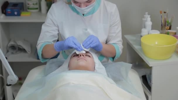 Esthéticienne professionnelle se frotte le visage avant la procédure avec des lingettes humides . — Video